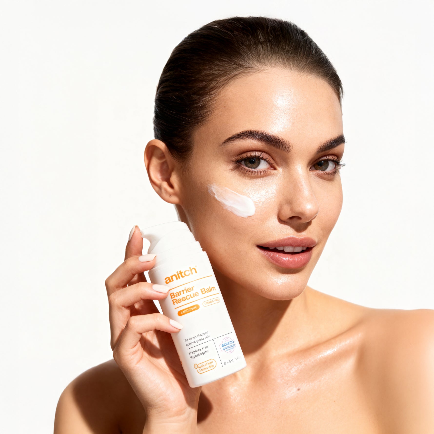 Woman applying sunscreen cream to her face with a white background