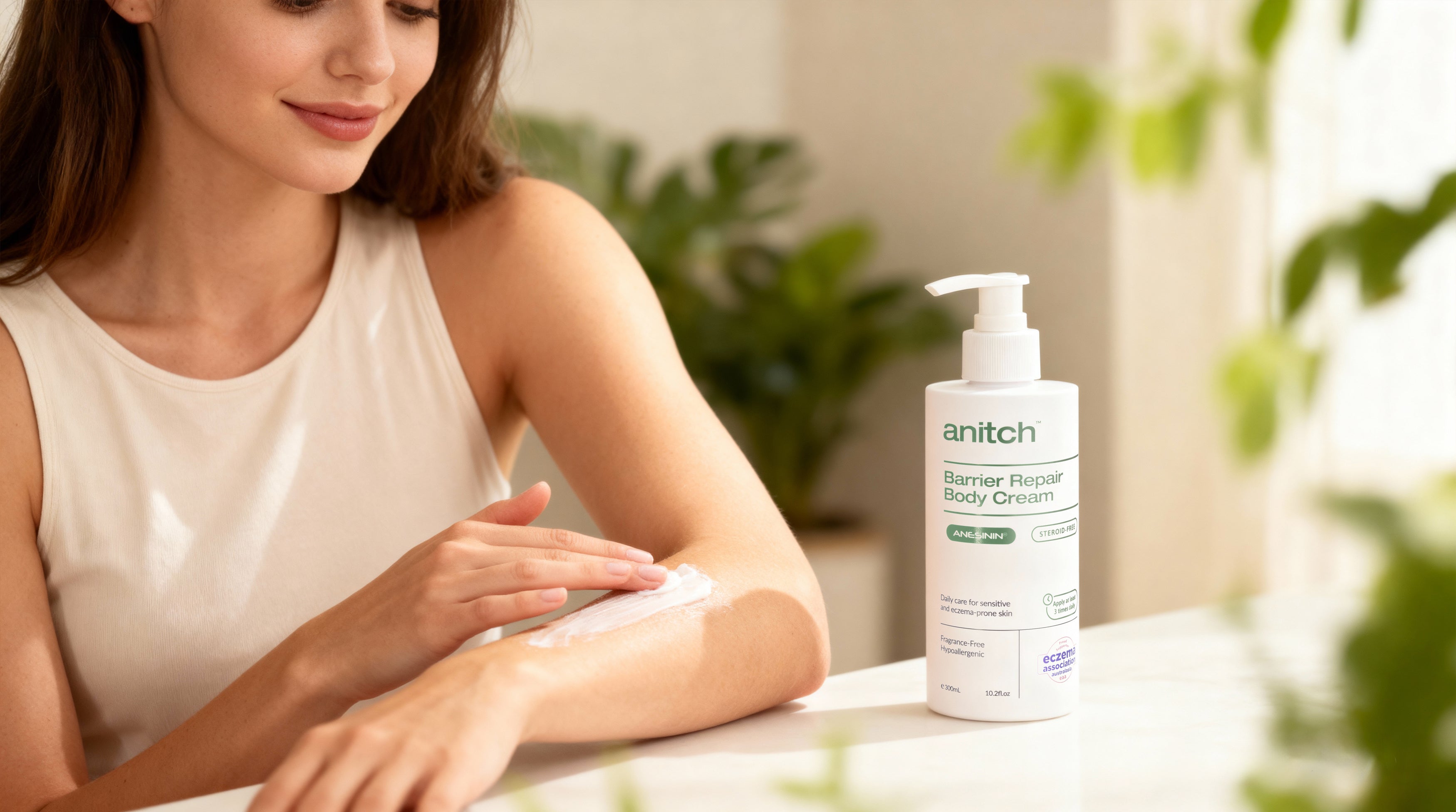 Woman applying cream to her arm with a bottle of 'anitch' cream on a table.